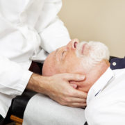 Closeup of a chiropractor adjusting a senior patient's cervical spine (neck).